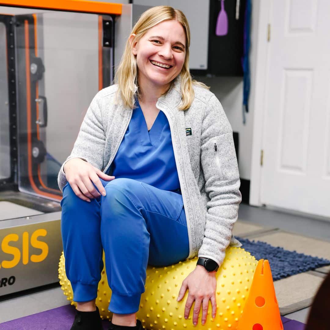 Vet sitting on a large yellow exercise ball